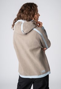 Beige fleece hoodie met een gestructureerd oppervlak, lichtblauwe accenten langs de naden en een capuchon met trekkoord. Voorzien van een lagere zoom.