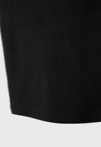 Tissu en coton noir avec une texture lisse, présentant un ourlet droit et un détail de couture fine le long du bord inférieur.