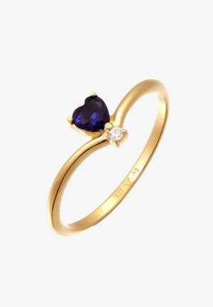 Goldring mit einem herzförmigen, tiefblauen Edelstein und einem kleinen klaren Stein als Akzent. Glatter Band mit polierter Oberfläche und minimaler Verzierungen.
