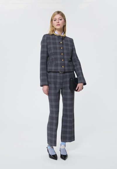 Costum gri cu carouri, cu o jachetă scurtă și pantaloni evazați, având butoane aurii și un design structurat. Plic negru și șosete albaștrii deschis.