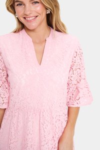Rosa spetsklänning med V-ringning och utsvängda ärmar, med blommönster och en texturerad yta. Tyget är semitransparent.