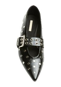 Zapato de piel negra con punta afilada, adornado con tachuelas plateadas y una correa ancha con hebilla. Textura suave, suela plana y forro interior minimalista.