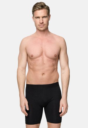 Boxer da uomo neri con un tessuto morbido e elasticizzato. L'elastico in vita presenta un branding discreto. Il modello è in posizione eretta, con il torso nudo, su uno sfondo neutro.