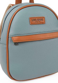 Mochila de imitación de cuero texturizado azul con acentos marrones, forma curvada, bolsillo frontal y una etiqueta con el logo. Cremallera y costuras detalladas.