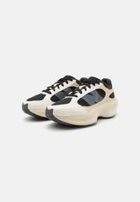 Snøresneakers med et hvidt, sort og beige design. Fremstillet af mesh og syntetiske materialer, med en struktureret sål og subtile detaljer.