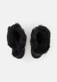Svarta fluffiga ankelstövlar med ett texturerat yttermaterial, mjuk syntetisk pälsfoder och rundad tådesign. Öppna upptill för enkel påtagning.
