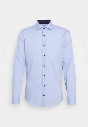 Camicia a maniche lunghe azzurro chiaro in cotone, con colletto a punta, bottoni neri e orlo curvo. Texture liscia senza motivi.
