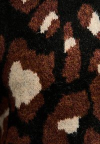 Bruine en zwarte gebreide stof met onregelmatige witte hartvormen die een textuur, patroon textiel in close-up creëren.