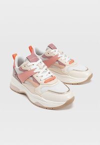 Baskets épaisses présentant un mélange de matériaux blancs, pêche et roses; éléments en mesh et cuir; bout rond; semelle texturée; branding visible.