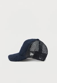 Granatowa czapka z teksturowanym, puszystym przodem i tylnymi panelami z siateczki, z zakrzywionym daszkiem i wyszywanym logo z boku.