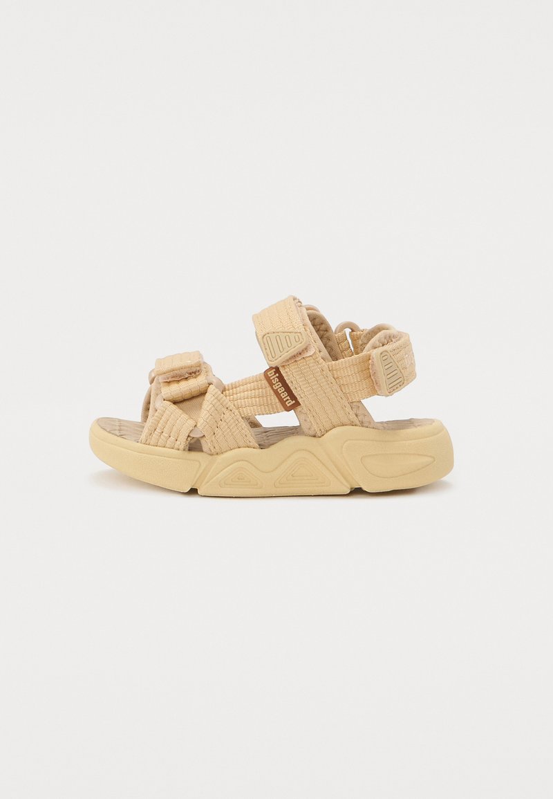 Beige Sandalen aus strukturiertem Stoff mit verstellbaren Riemen und einer Gummisohle, die ein geformtes Muster aufweist. Geschlossene Ferse.