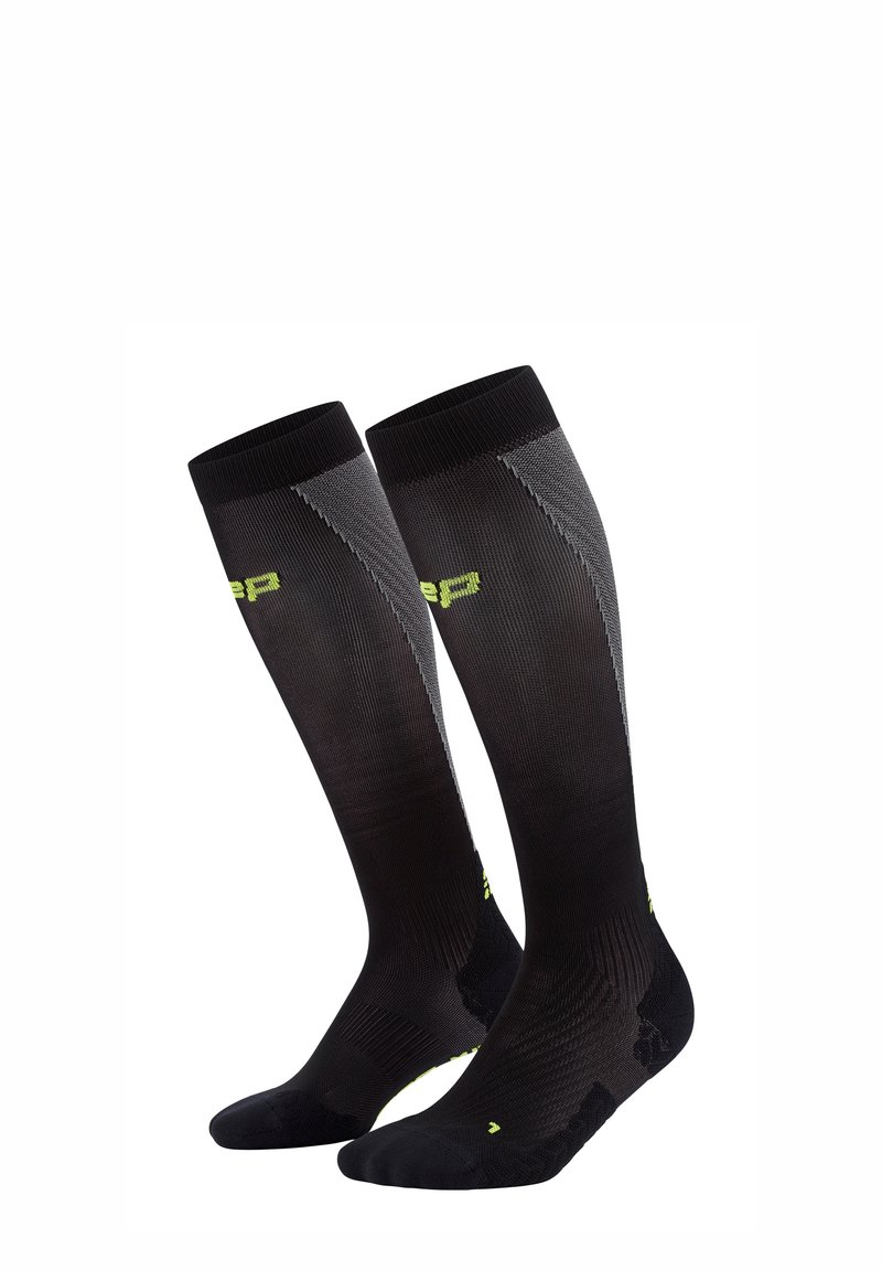 Calze nere alte fino al ginocchio con una texture a coste, accenti verde lime, e un design aderente per il supporto. Presentano aree della punta e del tallone rinforzate.