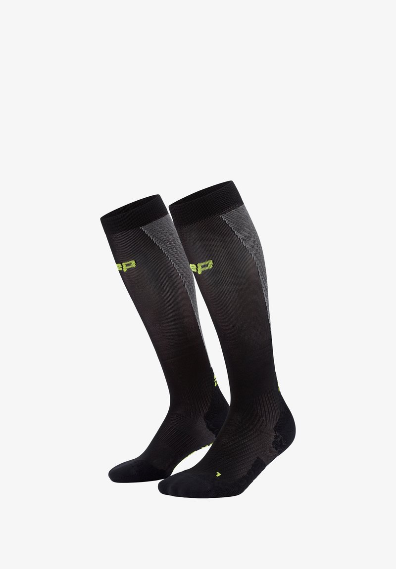 Calze nere alte fino al ginocchio con una texture a coste, accenti verde lime, e un design aderente per il supporto. Presentano aree della punta e del tallone rinforzate.