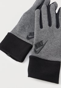 Szürke polár kesztyűk fekete mandzsettával, texturált felülettel és fekete Nike logóval a csukló részen.