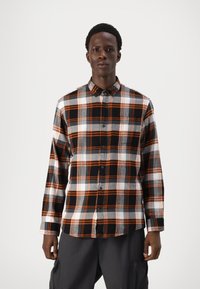 Zwart en oranje geruite blouse met lange mouwen, knoopsluiting aan de voorkant, witte en grijze accenten en een gebogen zoom. Geweven stof.
