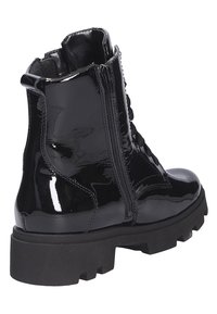 Botte de combat en cuir verni noir avec semelle épaisse à crampons, fermeture éclair latérale et laçage à l'avant, vue en angle de l'arrière.