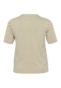 T-shirt beige à manches courtes, avec un motif à pois noirs. Encolure ronde et texture douce et lisse.