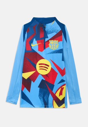 Nike dolgo rokav nogometni dres v modri barvi z abstraktnim vzorcem v rdeči, rumeni in črni barvi. Vključuje grb Barcelone in logotip Spotify.