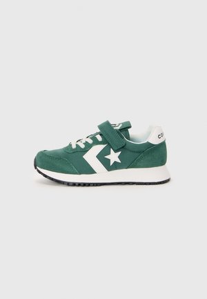 Zapatilla verde con parte superior de ante y textil, logo de estrella blanca y acentos, correa de velcro sobre los cordones y suela de goma negra.