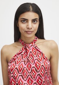 Abito senza maniche con scollo a halter in satin rosa, con un motivo floreale decorativo rosso e bianco, caratterizzato da un dettaglio anteriore annodato.