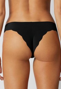 Black thong underwear with a scalloped waistband, featuring a smooth texture and minimal rear coverage, highlighting a clean design.