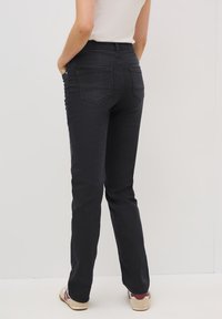 Zwarte denim straight-leg jeans met reguliere zakken, voorzien van een hoge taille en subtiele stikdetails. Draagt met een getailleerde top en schoenen.