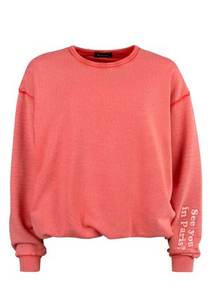 Coral oversized sweatshirt with a crew neck and cuffed sleeves. Features "See you in Paris?" text on the left sleeve. Soft material, relaxed fit.