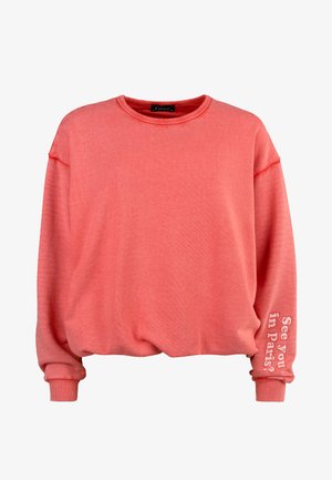 Coral oversized sweatshirt with a crew neck and cuffed sleeves. Features "See you in Paris?" text on the left sleeve. Soft material, relaxed fit.