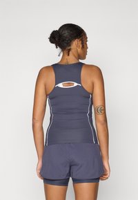 Top atlético azul-marinho com design de costas nadadoras, detalhes brancos e recortes. Combinado com calções azul-marinho coordenados para um visual harmonioso.