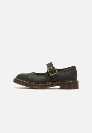 Zwarte leren Mary Jane-schoen met een gouden gesp, gele stiksels, decoratieve perforaties en een dikke bruine zool op een witte achtergrond.