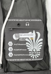Gray fabric with mesh accents. Features a zipper pocket, brand logo, and care symbols indicating waterproof and elastic properties.
