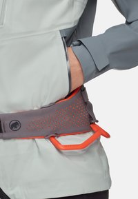 Grijze en witte lichtgewicht jas met een grijze riem met oranje accenten en perforaties. Inclusief een feloranje handvat.