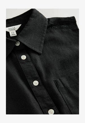 Sort linned shirt med klassisk krave, der har hvide knapper, en brystlomme og en fin blondedetalje på skulderen.