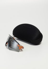 Ochelari de soare cu lentile gri, accente portocalii și un design sportiv, alături de un etui de protecție negru cu fermoar.