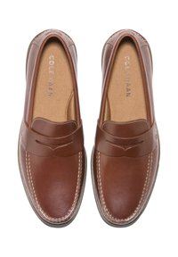 Une paire de mocassins en cuir marron avec des détails de couture et des semelles intérieures beige de la marque "Cole Haan" vue de dessus.