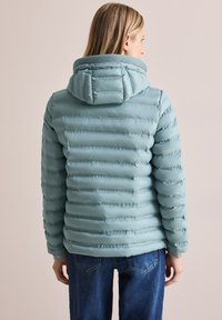 Ljusblå pufferjacka med horisontell sömnad, huva och ribbad krage. Slät yta med en figursydd form och elastiska ärmslut.