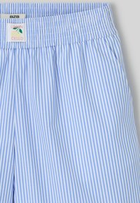 Shorts rayés bleu clair en tissu lisse ; avec une taille élastique, une étiquette avec un graphique de citron et des poches latérales.