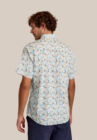 Kortaf shirt met een multikleurig bloemenpatroon op een lichtblauwe achtergrond, gemaakt van lichte stof met een klassieke kraag.