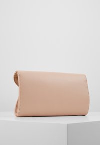 Portefeuille en cuir rose avec une texture lisse et un design à rabat. Il présente des bords arrondis et une surpiqûre sur les coutures.