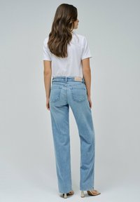 Pantalones vaqueros de tiro alto en azul claro, confeccionados en denim, con un diseño de pierna recta, bolsillos traseros y una etiqueta de cuero en la cintura.