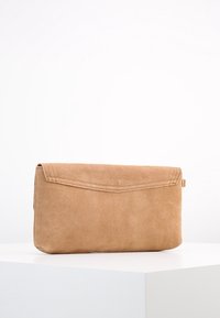 Vaaleanruskea mokkalaukku, jossa taitettava läppä, ommeltu yksityiskohta ja hillitty metalliosuus. Sileä pinta ja jämäkkä, suorakulmainen muoto.