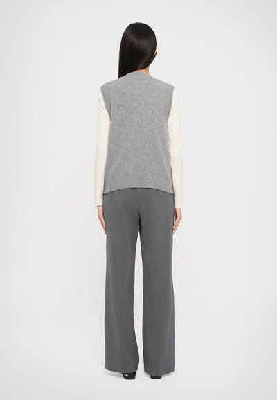 Gray sleeveless sweater with a ribbed hem, worn over a long-sleeve cream shirt and paired with wide-leg gray trousers. Smooth texture.