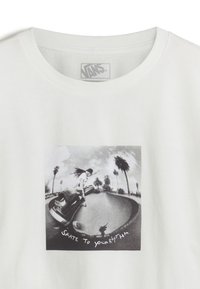 Witte katoen t-shirt met een zwart-wit grafiek van een skateboarder met palmbomen, en de tekst "SKATE TO YOUR RHYTHM" eronder.