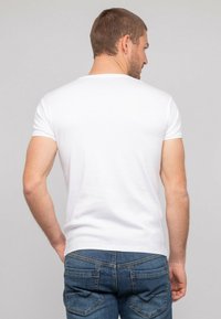 T-shirt blanc à manches courtes en coton, avec un col rond et une texture lisse, associé à un jean en denim bleu avec poches.