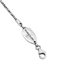 Silvervirad kedja med en charm-tag graverad "HAZE & GLORY 925" och en karbinhake. Har en slät metallisk yta och oval form.