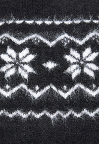 Zwarte gebreide stof met witte sneeuwvlok- en zigzagpatronen. De textuur is zacht met een iets fuzzy afwerking.