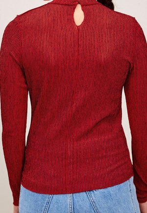 Camiseta de manga larga roja con detalles en forma de ojo de cerradura en la parte posterior. La tela tiene una apariencia texturizada con rayas verticales.