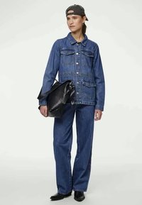 Denim jakk, millel on kaks rindtaskut ja nööbid, koos lohakate denim pükstega. Aksessuaaride hulka kuulub must kott ja tume müts. Mustad kingad.