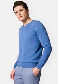 Niebieski sweter w serek wykonany z delikatnej dzianiny, z prążkowanymi mankietami i dołem. Prosta aplikacja logo na lewym piersiu.