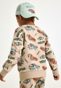 Beige sweatshirt met kleurrijke autoprints in verschillende stijlen, geribde cuffs en zoom. Teal pet met een autografiek, verstelbare achtersluiting.